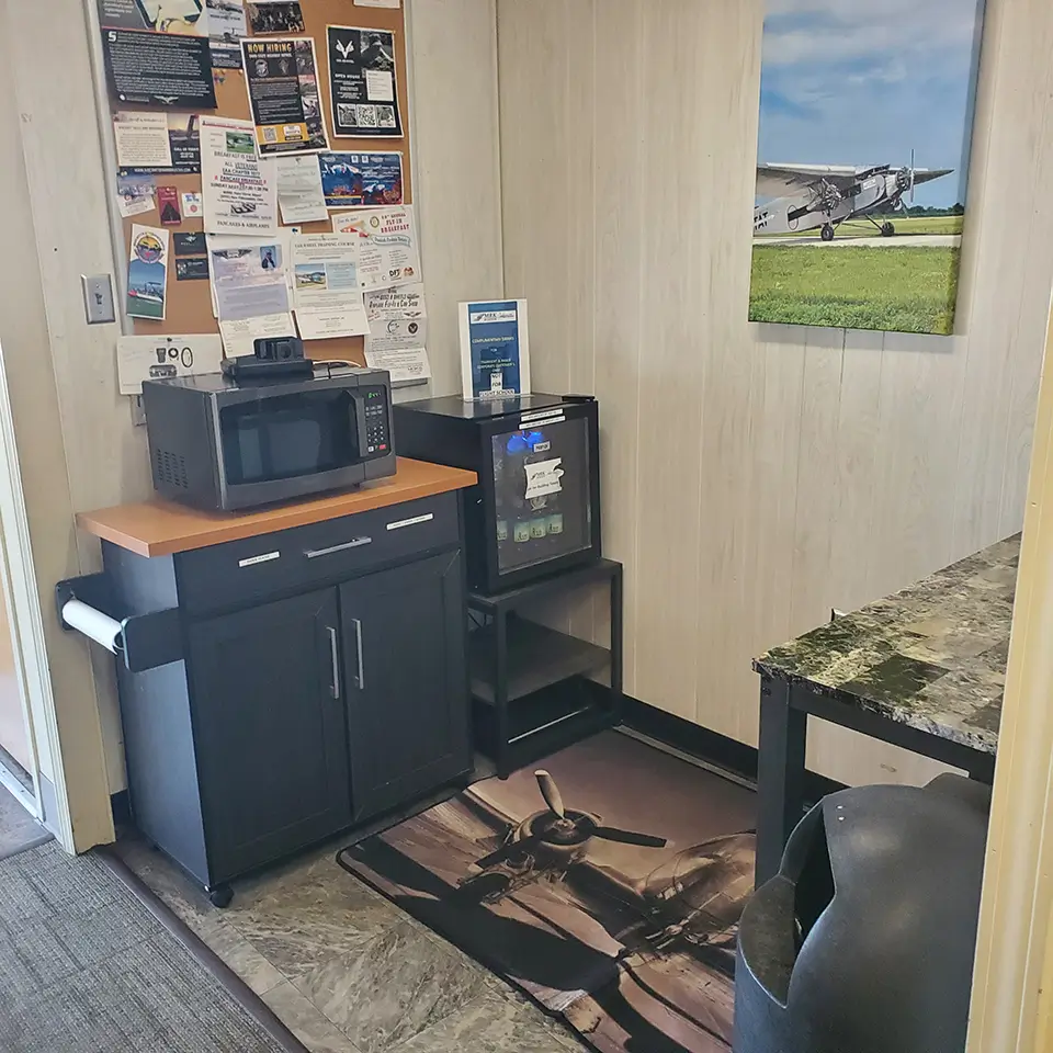 KLPR snack area with a microwave, snack fridge, prep counter, and community board