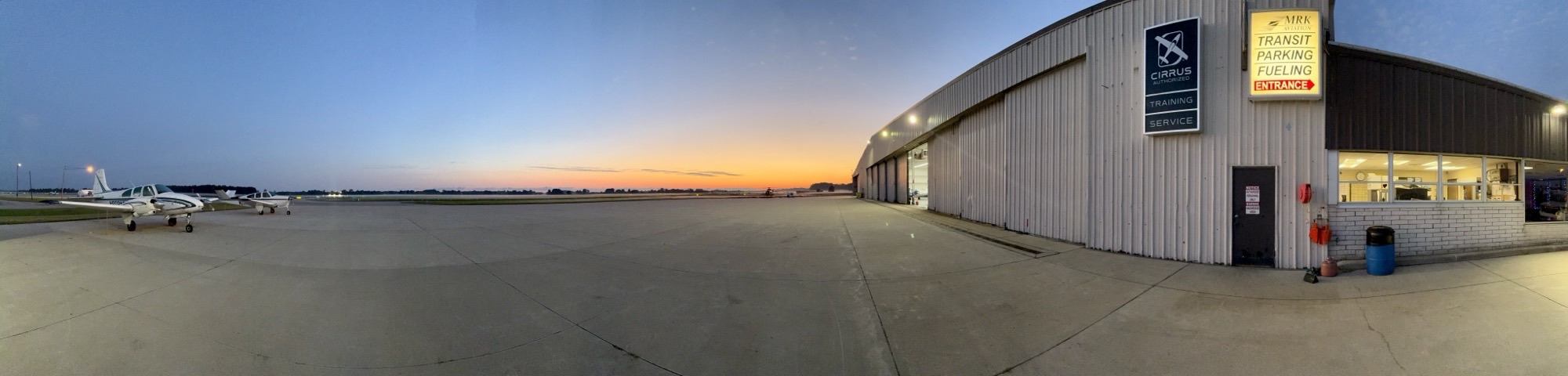 Panoramic view of the MRK Aviation ramp and hangars at dusk with parked aircraft