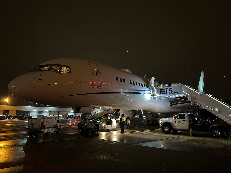Private charter aircraft on the ramp at night with JETS service truck and airstairs